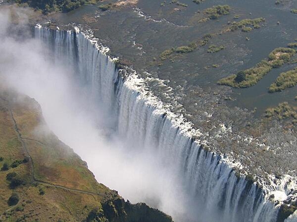 Victoria Falls is located between the borders of Zambia and Zimbabwe. During flood season (February to April), the falls form the greatest sheet of falling water on earth. Victoria Falls is 1.7 km (1.1 mi) wide and 108 m (360 ft) high and is known locally as Mosi-oa-Tunya (The Smoke that Thunders).  
View of Victoria Falls on the Zambezi River as seen from the Zambian (eastern) side.