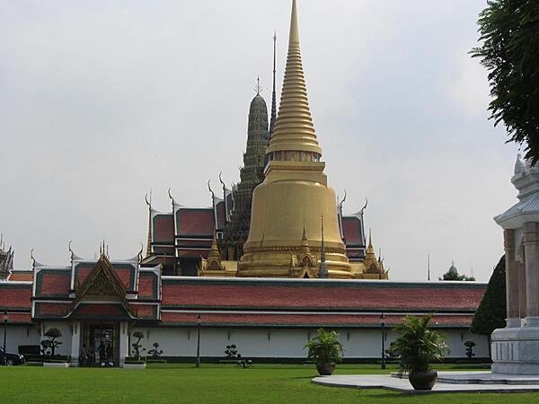View inside the Grand Palace in Bangkok, Thailand, showing the golden Phra Siratana Chedi. A chedi, or stupa, is a mound-like reliquary containing Buddhist relics. The chedi is on the grounds of the Temple of the Emerald Buddha.