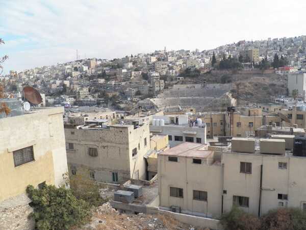 A view of Amman and the Roman Theater. The theater is located in the eastern part of the city on a hill opposite the Amman Citadel. The Roman Theater was built between A.D. 138 and 161 in honor of Roman Emperor Antoninus Pius.  With a northerly oriented design to keep the sun off the audience, the theater could seat up to 6,000 people who were separated by status, gender, and nationality. The Jordanian Government started  restoring the theatre in 1957 and today it is open to visitors and hosts many local events. The Roman Theater also houses the Amman Folklore Museum and the Amman Museum of Popular Traditions, both located in a series of rooms behind the two ground-level entrances.