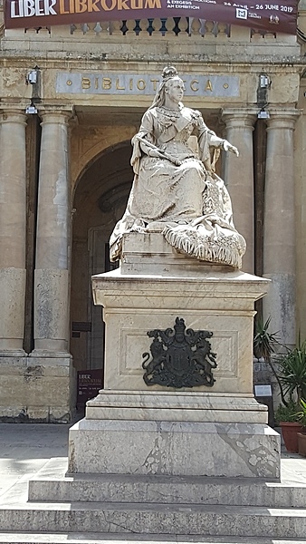 Statue of Queen Victoria outside Malta’s National Library in Republic Square, Valletta.  Erected in 1891, the monument commemorates Queen Victoria’s 50th jubilee and was paid for by public subscription. The statue, made of white marble on grey stone steps with two coats of arms in bronze, is the work of Sicilian sculptor Giuseppe Valenti and depicts the Queen sitting with a shawl of Maltese lace draped over her lap. Malta was a British colony for 150 years before gaining its independence in 1964 and declaring itself a republic in 1974.