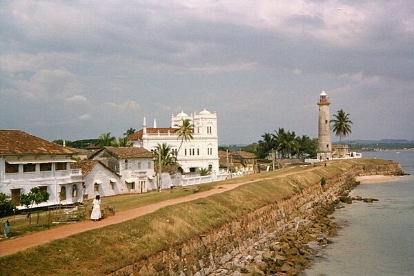 The Galle lighthouse is the oldest lighthouse in Sri Lanka, first built in 1848; it lies at the entrance to Galle harbor on southwestern coast of Sri Lanka, about 120 km south of Colombo. The lighthouse is situated within Galle Fort, first fortified by the Portuguese in 1588 and then extensively improved upon by the Dutch in the 17th and 18th centuries. The current lighthouse is 26.5 m tall and was built in 1939 after the original lighthouse was destroyed by fire in 1934. Galle was a historically important port of call in the Indian Ocean trade being visited by the Islamic explorer Ibn Batuta, the Chinese admiral Zheng He, and where the Portuguese first landed in 1502. Today, the lighthouse and surrounding fort have been designated as a World Heritage Center.