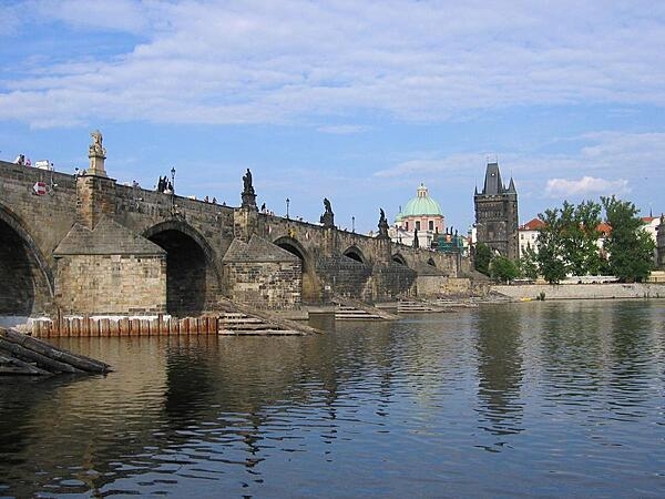 A riverside view of Charles Bridge in Prague showing the ice guards that protect the pillars.