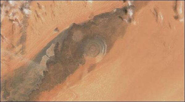 The Richat Structure, a prominent circular feature in the Sahara Desert of Mauritania, has attracted attention since the earliest space missions because it forms a conspicuous bull&apos;s-eye in the otherwise rather featureless expanse of the Gres de Chinguetti Plateau in central Mauritania. The Structure, which has a diameter of almost 50 km (30 mi), has become a landmark for space shuttle crews. Initially interpreted as a meteorite impact structure, it is now thought to be merely a symmetrical uplift (circular anticline) laid bare by erosion. Image courtesy of NASA.