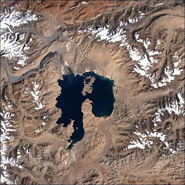 Near the center of this scene is the mountain lake Kara-Kul, located in eastern Tajikistan, high in the Pamir Mountain Range near the Afghan border. The 25-km (16-mi) diameter lake sits at an elevation of about 4,000 m (about 12,000 ft) above sea level. Kara-Kul was formed from a meteorite impact approximately 25 million years ago, leaving a crater with a rim diameter of 45 km (28 mi). Islands formed from the central uplift can be seen in the northern and southern parts of the lake. Interestingly, the Kara-Kul impact structure remained unidentified until it was discovered though studies of imagery taken from space. Photo courtesy of NASA.