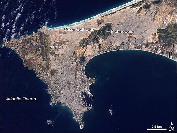 In the 1940s, Dakar occupied just the southern tip of the Cap Vert Peninsula. Today, the cityscape has sprawled both northward and eastward. In the southern part of this satellite view, piers from the peninsula protrude into the ocean, looking like rows of jagged teeth. Throughout the southern portion of the peninsula, gray hues, straight lines, and sharp angles reveal paved roads and buildings spreading toward the north. In the northwest, a long, straight line outlined by green indicates the runway of Dakar&apos;s airport. East of the airport, a large area of green reveals Technopole, a protected area and popular bird-watching destination. Photo courtesy of NASA.