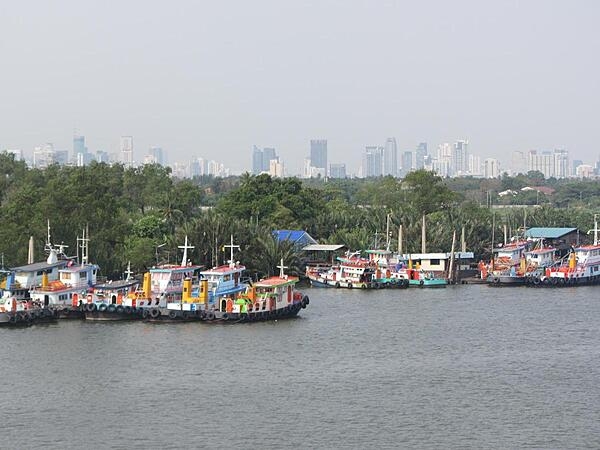 Fishing boats on the Chao Phraya River with the skyline of Bangkok in the background.