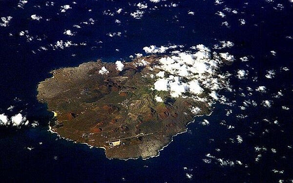 An oblique view of rugged Ascension Island, which is is barren in many places and has no indigenous human population. Instead the residents of the island are there because of Ascension&apos;s main industry: communications. The island has a long history as a communications hub for telephone and radio communications and as a base for satellite tracking stations, including a NASA station built in the 1960s that no longer operates. The European Space Agency operates a tracking station for its Ariane spacecraft on the eastern side of the island. 

Ascension Island is one of the most important breeding grounds for seabirds in the tropical Atlantic Ocean. The population of seabirds has been under threat since the first humans sailed up to the island in the 1500s. The ships accidentally introduced black rats, which overran the island, until cats were introduced to curb the rat population. The feral cats have decimated the bird populations, and in fact, are probably responsible for the extinction of two of the islands native land birds. A restoration project is underway to control the cat population and revive the seabirds. Image courtesy of NASA.