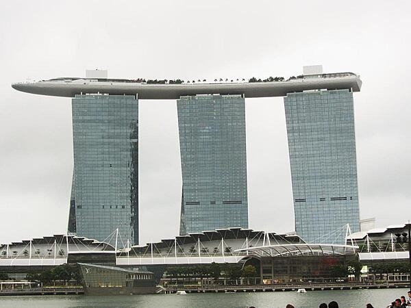 View of the Marina Bay Sands complex in Singapore that opened in 2010 and has since become a city landmark. The three 55-story towers contain hotel rooms. The upper level Sky Park, built to resemble a ship, has the world&apos;s longest elevated swimming pool, restaurants, gardens, and a public observation deck. The integrated resort also includes an adjacent ArtScience Museum, a casino, and a convention center.