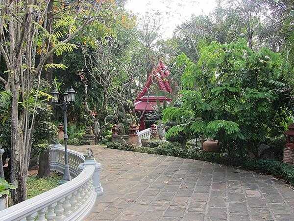 The Prasart Museum in Bangkok, Thailand, houses an extensive private collection of historic Thai culture amassed by a wealthy Thai businessman and features a collection of Thai buildings placed along pathways in a Garden of Serenity. Shown here is a pathway in the Garden of Serenity on the museum grounds; a chapel appears in the background.