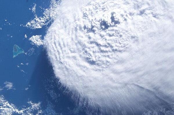 A large cloud bank moves in on Aitutaki Atoll in the Southern Cook Islands. Image courtesy of NASA.
