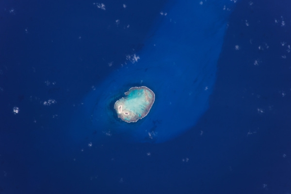 Rocas Atoll, here viewed from the International Space Station, is the only atoll in the South Atlantic Ocean. Part of the Fernando de Noronha archipelago, it is located approximately 260 km (160 mi) off the northeastern coast of Brazil. The image clearly captures the defining boundary between the outer algal ridge, the open ocean, and the sandy bottom closer to the atoll’s center. In 1978, Rocas Atoll was named a national biological reserve due to its large populations of migratory and resident seabirds. As the first marine reserve to be established in Brazil, the remote, uninhabited atoll is used strictly for scientific research. An atoll is usually a circular or oval-shaped reef structure with a lagoon in the center. These structures typically form around a volcanic island that has subsided while the coral continues to grow upward.  Photo courtesy of NASA.